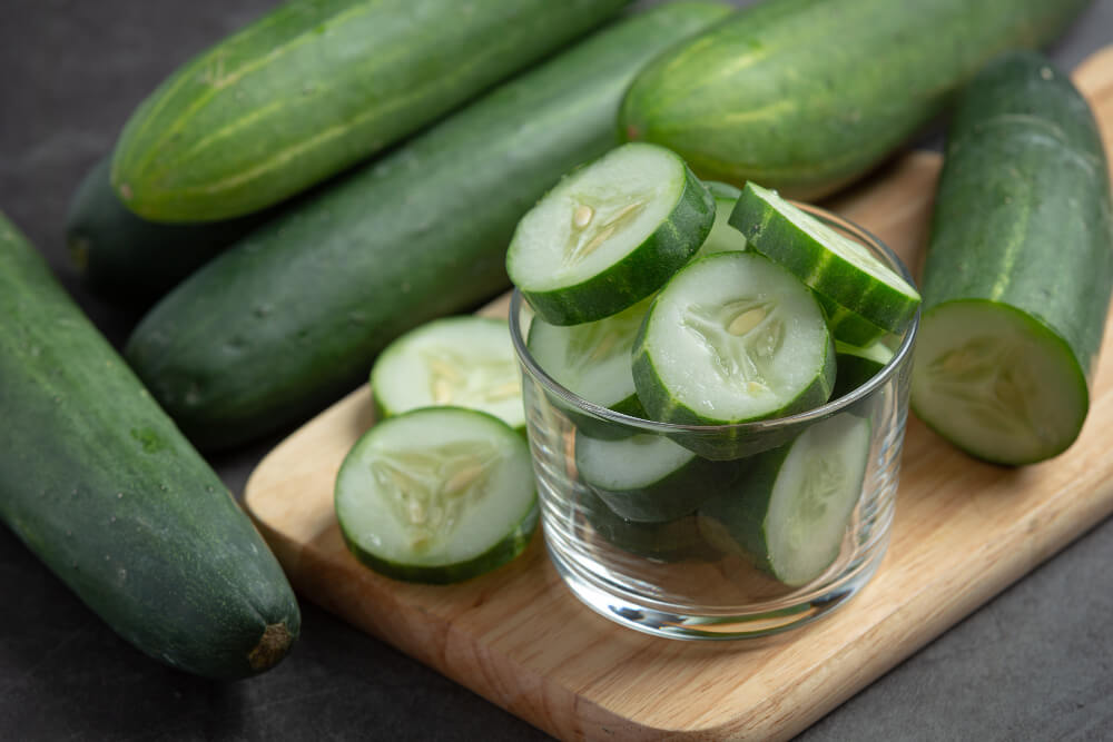 Fresh cucumbers and slices in a glass bowl, known for hydrating and brightening skin naturally.